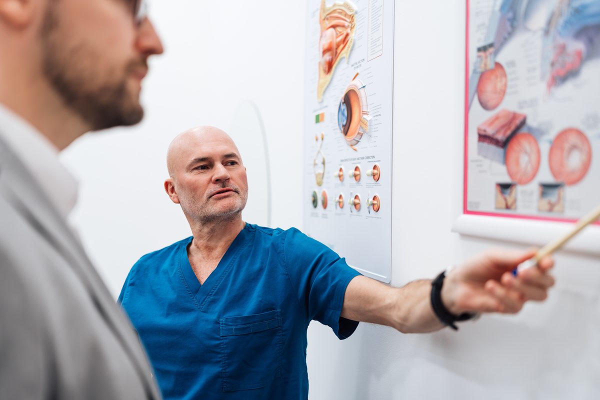 ophthalmologist pointing to an eye anatomy chart while explaining it to a patient